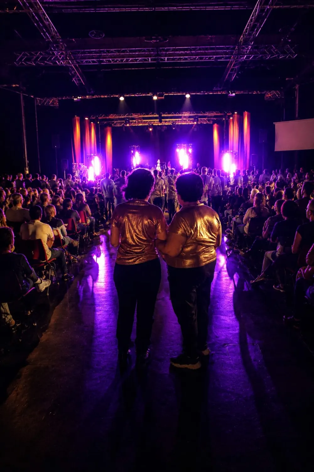 Nadège et Laure, de dos, face au public et à la scène lors d'un concours Osons Chanter